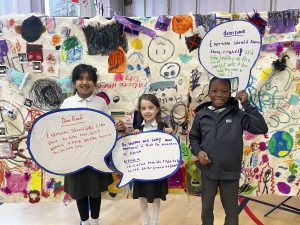 Children holding speech bubbles up with anti-racism sentences on.